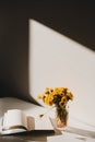 A book and a bunch of yellow dandelions.  Still life with wild flowers.  Play of light and shadow. Summer flowers Royalty Free Stock Photo