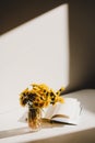 A book and a bunch of yellow dandelions.  Still life with wild flowers.  Play of light and shadow. Summer flowers Royalty Free Stock Photo