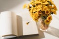 A book and a bunch of yellow dandelions.  Still life with wild flowers.  Play of light and shadow. Summer flowers Royalty Free Stock Photo