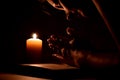 Book, candle and hands. Woman prays in dark. Reading prayers at night. Royalty Free Stock Photo