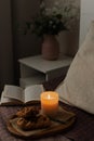 A book, candlelight, and baked goods on a wooden tray. The cozy atmosphere of home