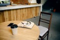 Book, coffee and glasses on table in student cafe