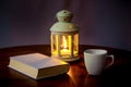 A book and a cup of coffee in the light of a lantern with a candle in the evening_ Royalty Free Stock Photo