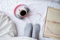 Book and cup of coffee on white bed with copy space.