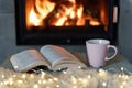 Book and cup of tea near fireplace Royalty Free Stock Photo