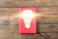 Book, electric light bulb from wooden puzzles on a wooden background. Royalty Free Stock Photo