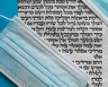 The Book of Esther is written in Hebrew on parchment next to colored surgical masks to prevent infection with the corona virus, on