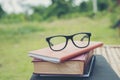 Book and eye glasses for read and write over blurred nature outdoor background.