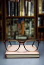 A book with eyeglasses on top of it, home library on background