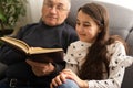 Book, family and children with a girl reading to her grandfather on the floor of their living at home. Kids, read and Royalty Free Stock Photo