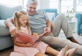 Book, family and children with a girl reading to her grandfather on the floor of their living at home. Kids, read and Royalty Free Stock Photo