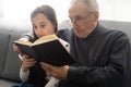 Book, family and children with a girl reading to her grandfather on the floor of their living at home. Kids, read and Royalty Free Stock Photo