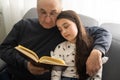 Book, family and children with a girl reading to her grandfather on the floor of their living at home. Kids, read and Royalty Free Stock Photo