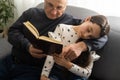 Book, family and children with a girl reading to her grandfather on the floor of their living at home. Kids, read and Royalty Free Stock Photo