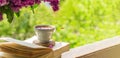 Book, glasses, cup of tea and lilac on a wooden window. The bee flies beautifully over the lilac petals Royalty Free Stock Photo