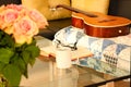 Book, glasses, roses and a mug with tea on modern glass table. An acoustic Spanish guitar is lying on an old rug on a black leathe Royalty Free Stock Photo