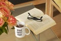 Book, glasses, roses and a mug with tea and text saying Home Sweet Home on modern glass table. Living room interior home decor con