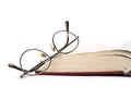 Reading glasses beside an old book. Isolated on a white background Royalty Free Stock Photo