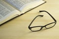 Book and glasses on a wooden table.