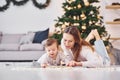 With book that is on the ground. Mother with her little daughter is indoors at home together Royalty Free Stock Photo