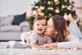 With book that is on the ground. Mother with her little daughter is indoors at home together Royalty Free Stock Photo