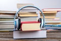 Book with headphone in front of piles of different books