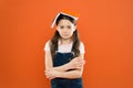 Book on her head. Little girl book roof head. Small girl book orange background. Interesting story for kid. Studying and