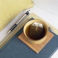 Cup of tea with book, journal and pen on chair with pillow. Relaxing, comfortable home interior elements details.