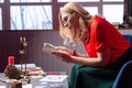 Blonde-haired female diviner feeling busy while reading book for magicians Royalty Free Stock Photo