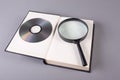 Book with magnifying glass and compact disk