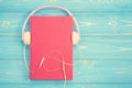 Book and new modern pink music headphone on blue wooden plank ba Royalty Free Stock Photo