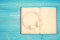 Book and new modern pink music headphone on blue wooden plank ba Royalty Free Stock Photo