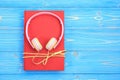 Book and new modern pink music headphone on blue wooden plank ba Royalty Free Stock Photo