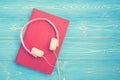 Book and new modern pink music headphone on blue wooden plank ba Royalty Free Stock Photo