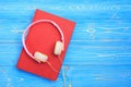 Book and new modern pink music headphone on blue wooden plank ba Royalty Free Stock Photo