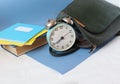 Book, notebooks and briefcase with a clock on a white background, close-up, side view