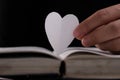 Book with open pages and heart shaped paper. Woman hand holding heart shaped paper over open book on table. love of reading Royalty Free Stock Photo