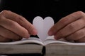 Book with open pages and heart shaped paper. Woman hand holding heart shaped paper over open book on table. love of reading Royalty Free Stock Photo