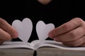 Book with open pages and heart shaped paper. Woman hand holding heart shaped paper over open book on table. love of reading Royalty Free Stock Photo