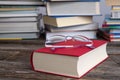 Book and reading glasses in front of piles of different books