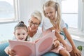 Book, reading and grandmother with children for learning, language development and English education in living room sofa Royalty Free Stock Photo