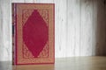 Book in a red cover on a white wooden background. layout for Bible, Koran, etc. selective focus. copy space