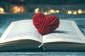 A book with a red heart on a dark background with lights.