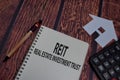 Book about REIT - Real Estate Investment Trust isolated on wooden table