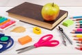 Book, school accessories and autumnal leaves on white boards, back to school concept Royalty Free Stock Photo