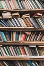 Book shelf with old books. Vertical background of a shelf with books. Old atmospheric library