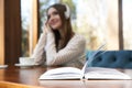 Book on table in cafe and woman with headphones on background