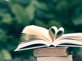 Book on table in garden with top one opened and pages forming heart shape Royalty Free Stock Photo