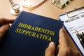 Book with title Hidradenitis Suppurativa on a desk.