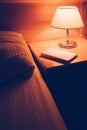 Book and vintage lamp on night table in hotel room Royalty Free Stock Photo